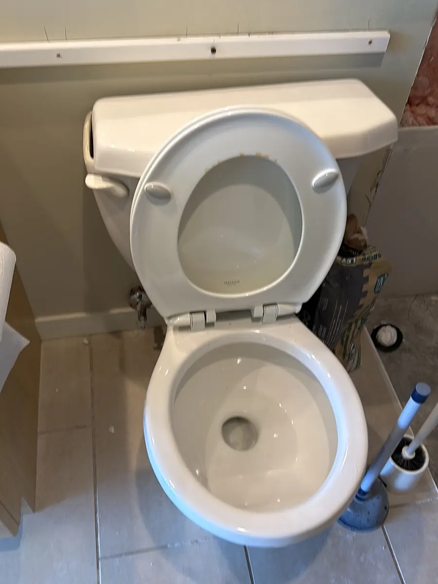 Old toilet in a tiled bathroom before replacement