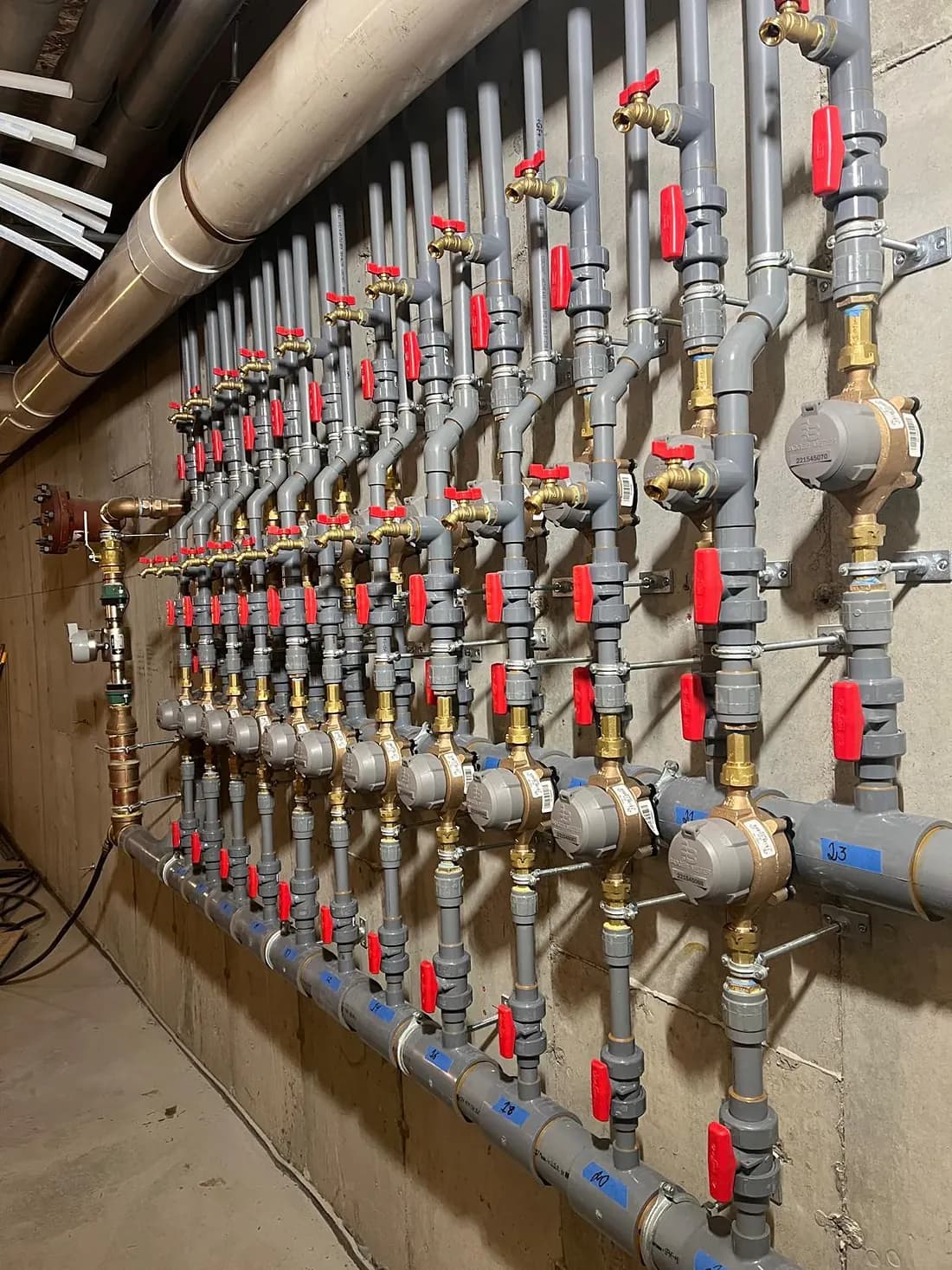 Copper water supply manifold with shutoff valves on a basement wall, the main water shutoff every homeowner should be able to find fast