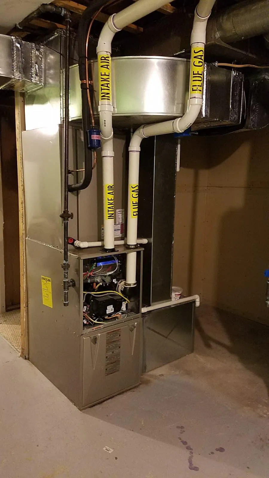 High-efficiency gas furnace with white PVC venting in a basement